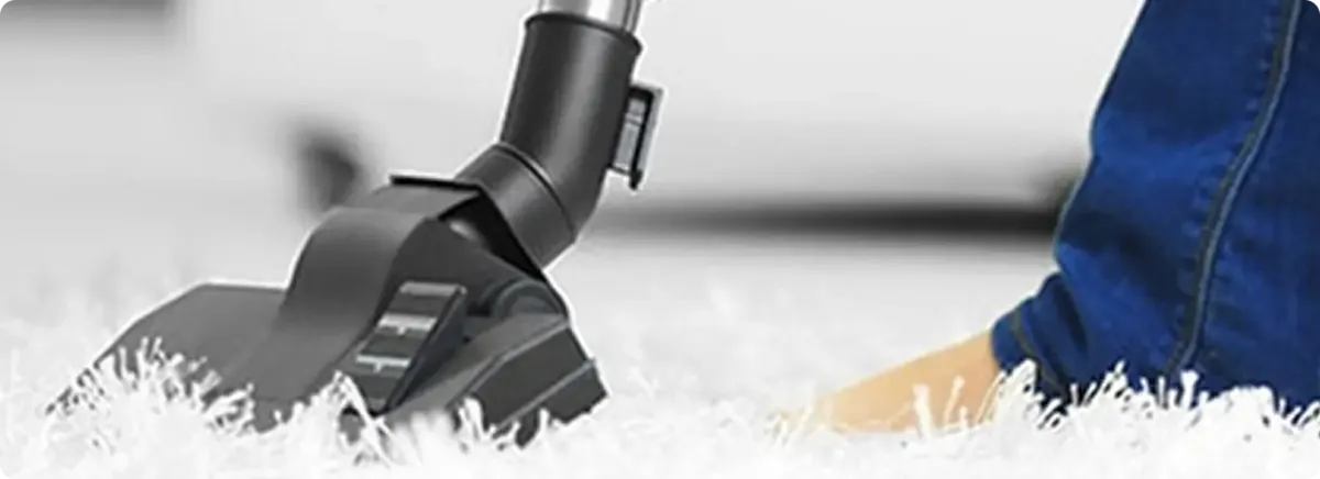 Close-up of a professional vacuuming a white carpet in Jones.